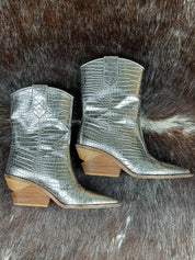 Silver metallic cowboy boots with wooden soles on a fur surface