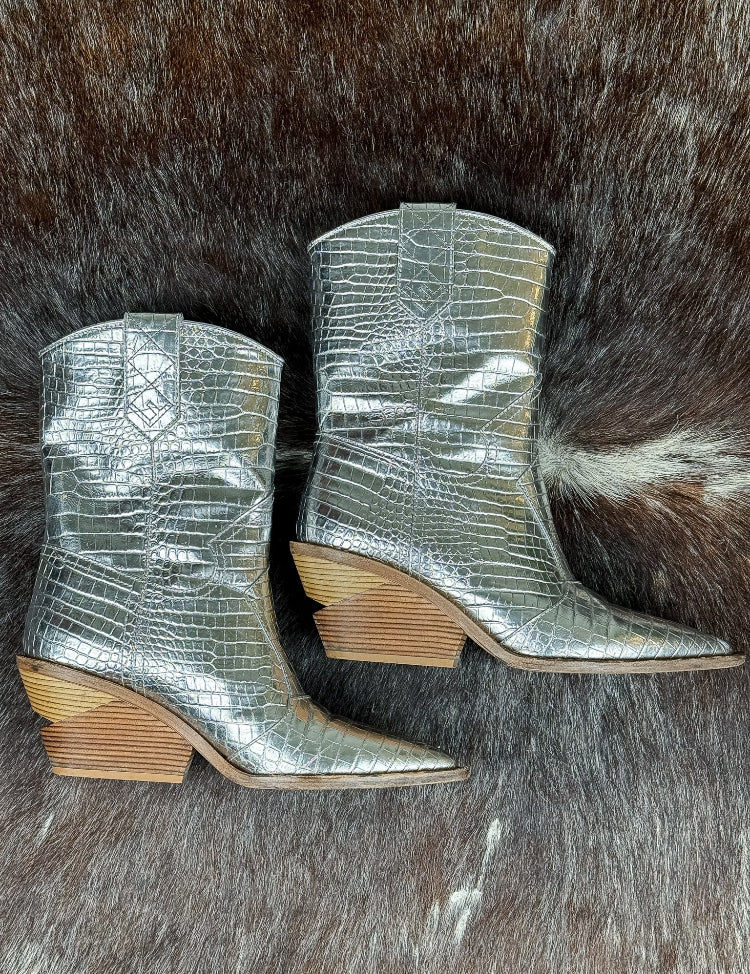 Silver metallic cowboy boots with wooden soles on a fur surface